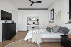 a bedroom with a bed, desk and ceiling fan in the middle of the room