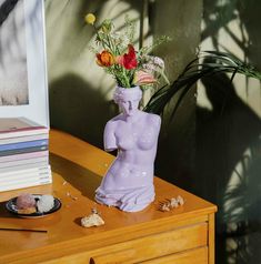 a vase with flowers in it sitting on a table next to a plate and books