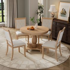 a round dining table with four chairs around it in a living room next to a window