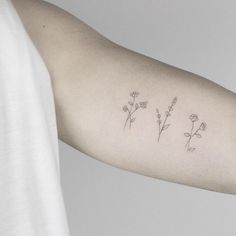 a woman's arm with three small flowers on the left side of her arm