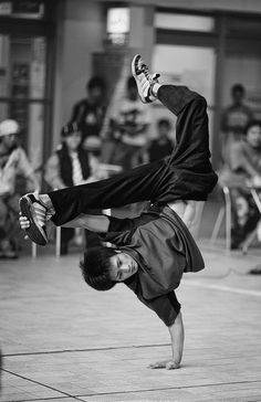 a man is doing a handstand on the ground while people watch in the background