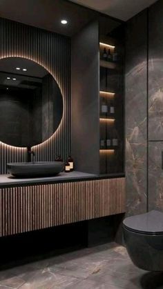 a modern bathroom with marble walls and flooring, black countertops and a round mirror on the wall