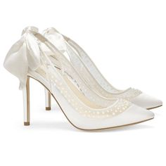 a pair of white high heels with bows on the heel and pearls at the toe