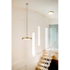 a light that is hanging from the ceiling in a room with some stairs and windows