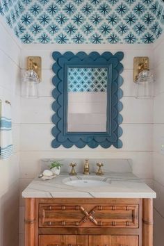 a bathroom with blue and white decor on the wall, sink and mirror above it