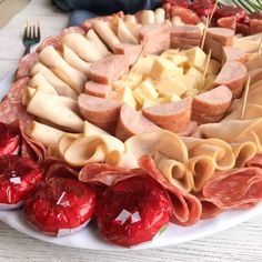 a platter filled with lots of different types of meats and cheese on sticks