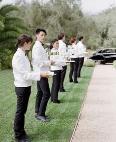 a group of people standing next to each other on top of a grass covered field