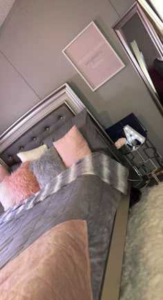 a bed with pink and grey pillows on it