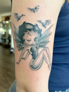 a woman's arm with a tattoo on it that has bats flying around her