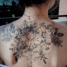 the back of a woman's neck with flowers tattooed on her upper and lower back