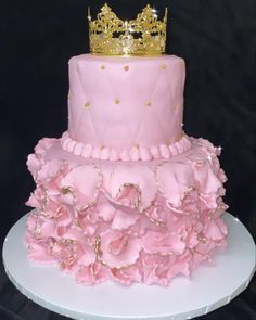 a three tiered cake with pink ruffles and a gold crown on top