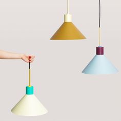 three different colored lamps with one being held by a person's hand and the other is