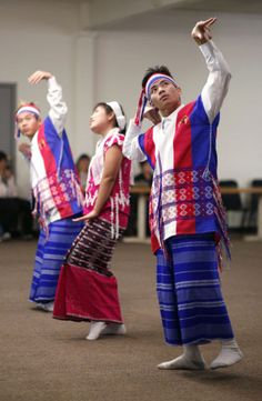 some people are doing something in the air with their hands up and one is wearing a colorful outfit