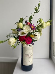 a vase filled with flowers sitting on top of a white table next to a window