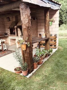 an outdoor kitchen with potted plants on the porch and in pots hanging from the roof