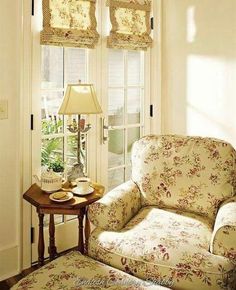 a living room filled with furniture and a lamp on top of a small wooden table