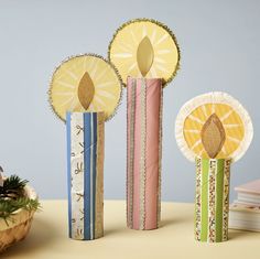 three decorative candles sitting on top of a table next to a basket and pine cone