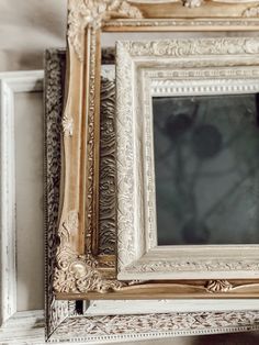 an ornate white and gold framed mirror on the wall