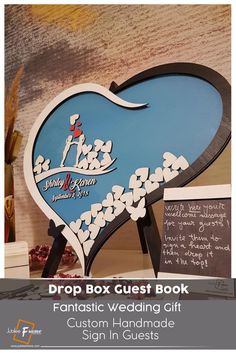 a sign that says drop box guest book and has a heart shape with flowers on it