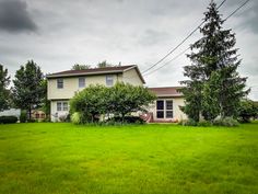 a white house sitting in the middle of a lush green field on a cloudy day