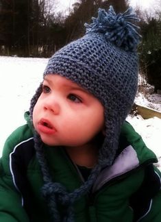 a small child wearing a knitted hat in the snow with text overlay that reads toddler ear flap hat free crochet pattern