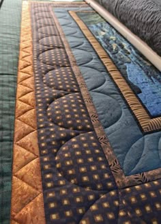 a close up view of a quilted bed with blue and gold designs on it