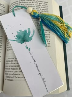 an open book with a tasseled bookmark on top of it next to some books