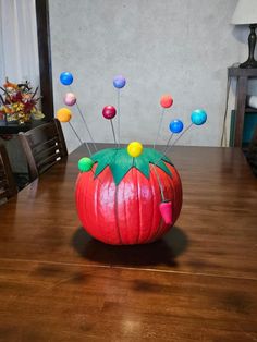 a pumpkin decorated with pins sitting on top of a wooden table