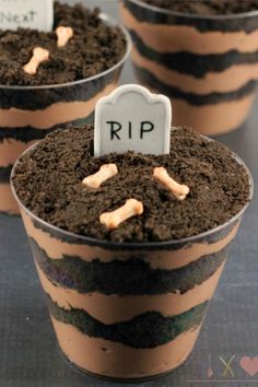 three cups filled with dirt and small tombstones on top of each cup are labeled rip