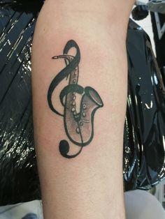 a tattoo with a musical note on it's arm and a snake in the shape of a treble