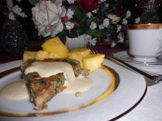 a white plate topped with food next to a cup and saucer on top of a table