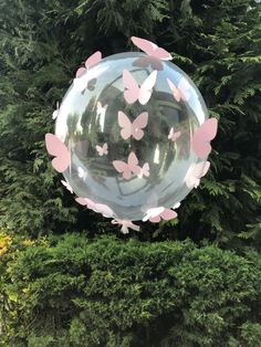 a large bubble filled with pink butterflies floating in front of a lush green park area