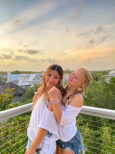 two young women standing next to each other on a balcony