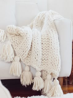 a white blanket sitting on top of a couch covered in tassels