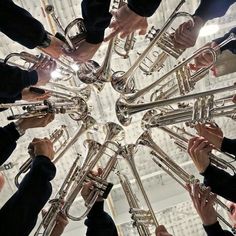 a group of people holding musical instruments in the middle of a circle with their hands together