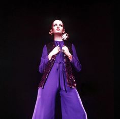 a woman in purple is performing on stage