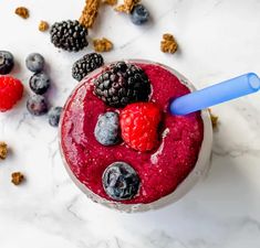 a smoothie with berries, blueberries and granola in it on a marble surface