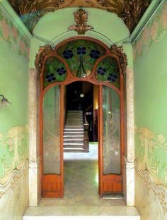 an entrance to a building with green walls and ornate decorations on the front door, along with steps leading up to it