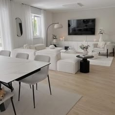 a living room filled with white furniture and a flat screen tv mounted on the wall