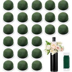 a vase filled with lots of green balls next to some white flowers and two black poles