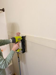 a woman is using a drill to fix a hole in the wall