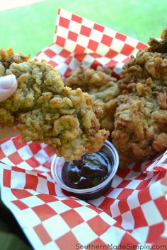 the fried food is being held up by someone's hand with ketchup