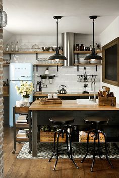 a kitchen with two stools and an island in the middle, surrounded by brick walls