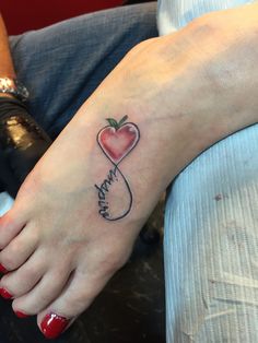 a woman's foot with a heart shaped apple tattoo on her left foot and the word love written in cursive writing