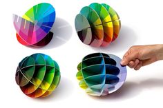 a hand is pointing at four different colored paper balls