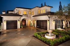 a large white house with lots of windows and lights on it's front door