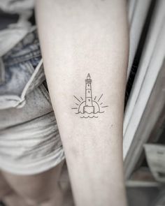 a small lighthouse tattoo on the arm