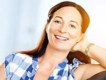 a smiling woman sitting in a chair with her arm on the back of her head