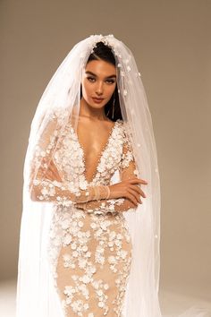 a woman in a wedding dress with flowers on her head and veil over her shoulder