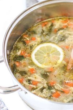 a pot full of soup with lemon, carrots and broccoli in it